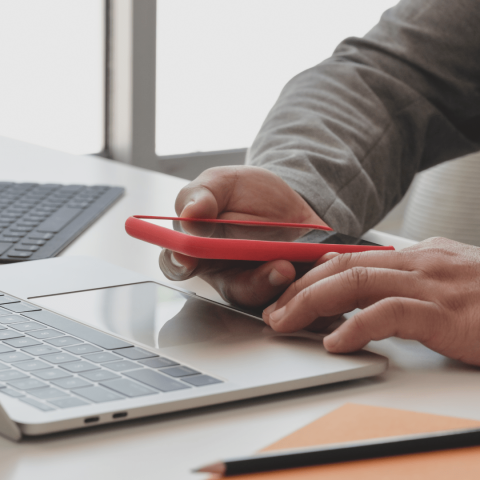 Persona mirando el móvil sobre un portátil